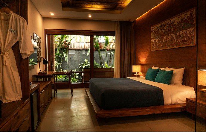 A made-up hotel room opening onto a garden